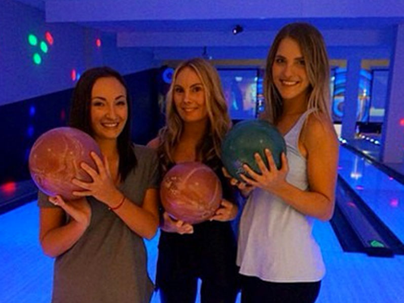 Three girls posing with bowling balls at AMF bowling