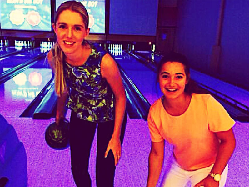 Two girls bowling facing the wrong side