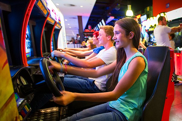 Teens playin driving games at the arcades