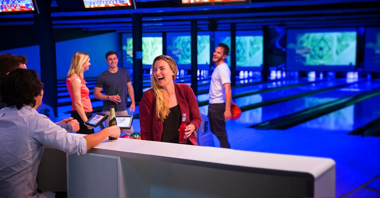 Friends have a drink and share laugh at the bowling alley
