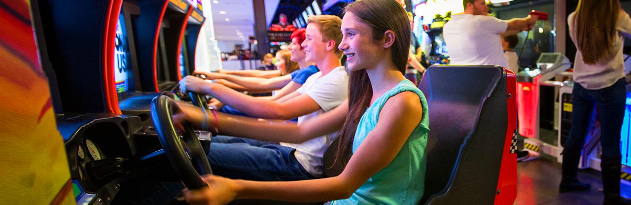 Teens playing driving games at the arcade