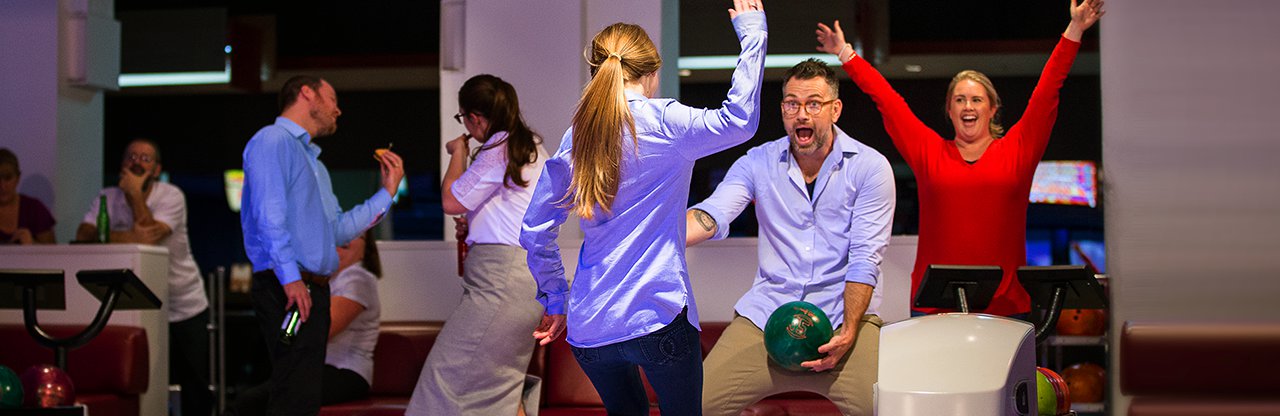 Adults celebrate a strike at bowling